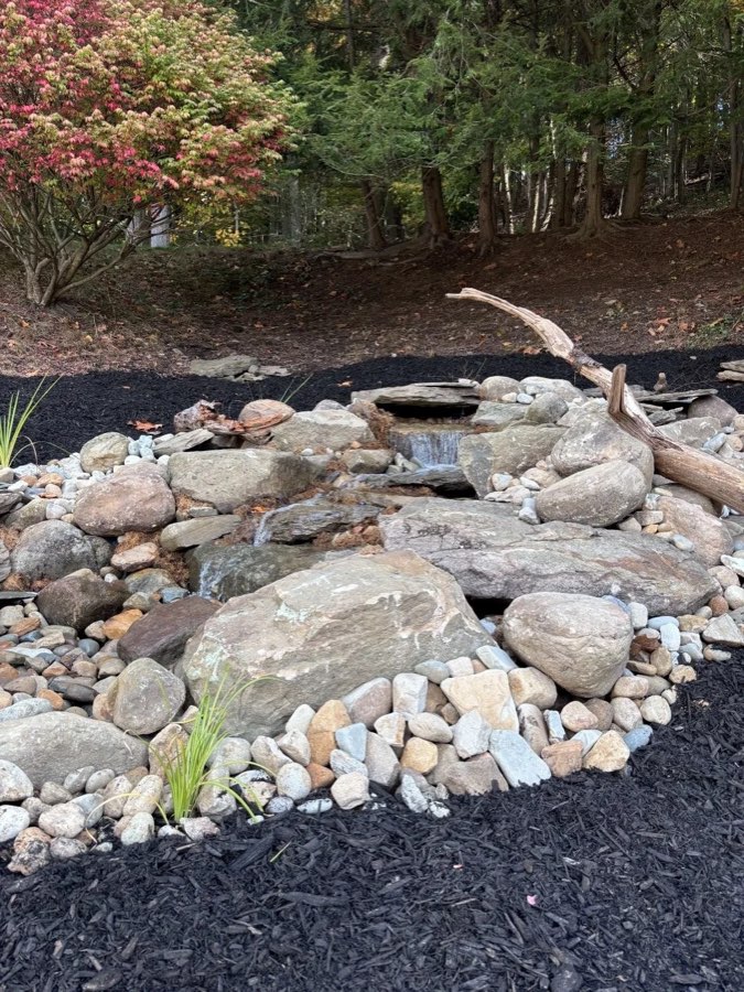 Natural stone water feature with river rock and plantings